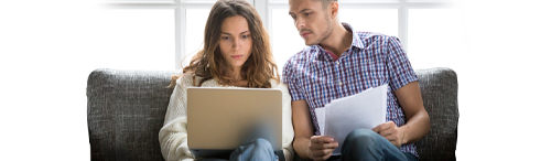 intense young couple considers mortgage loan information on laptop
