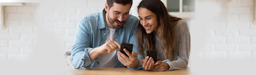 Millennial couple reviews mortgage loan details on cell phones