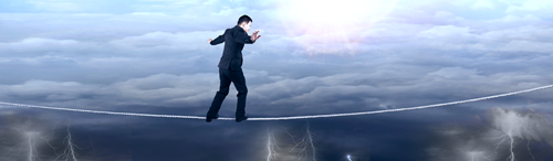 businessman on a tightrope over a stormy sky below with a lighter sky showing above